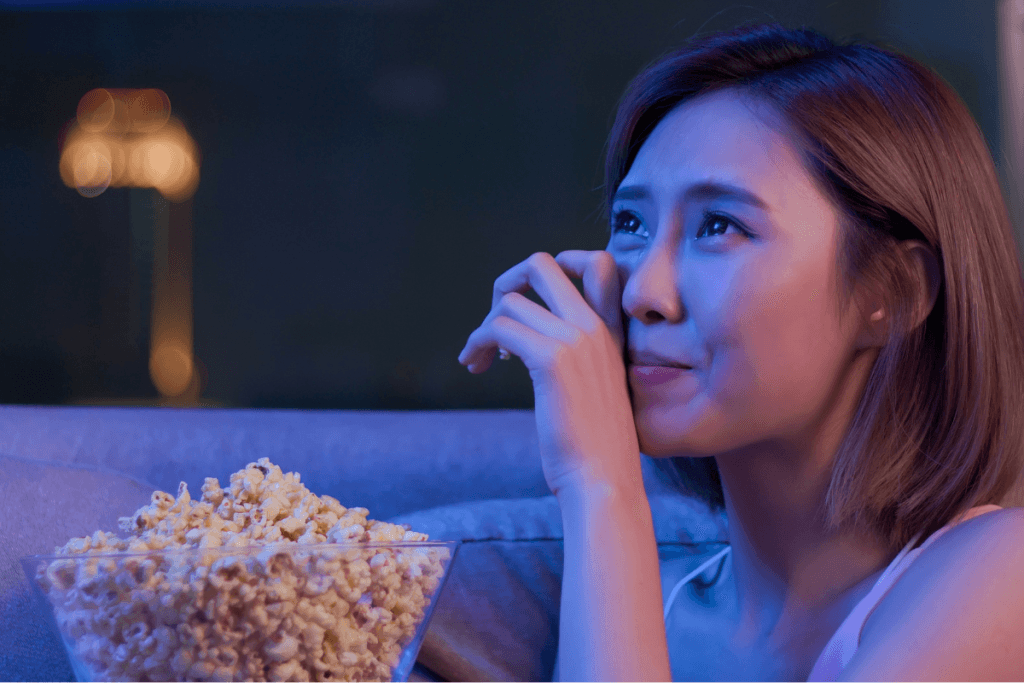 mulher chorando ao assistir filmes de romance e com uma pipoca na mão